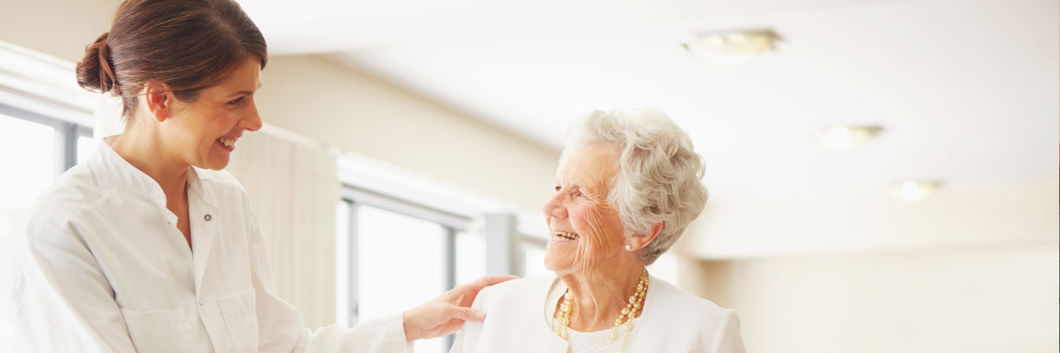 caregiver and elderly woman smiling and talking